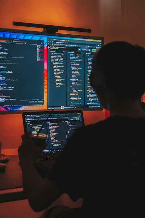 Développeur de dos face à des écrans de code